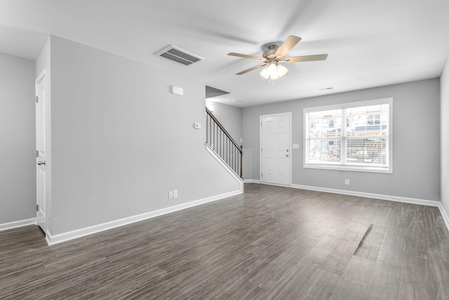 unfurnished living room with stairway, ceiling fan, baseboards, dark wood-style flooring, and visible vents