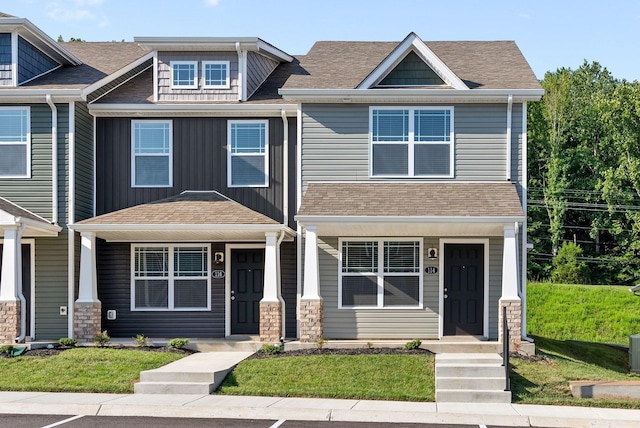 view of front of house featuring board and batten siding, a shingled roof, a porch, and a front lawn