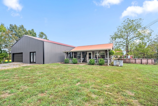 back of house featuring a garage, a porch, an outbuilding, and a yard