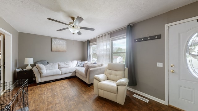 living room featuring ceiling fan, a textured ceiling, and dark hardwood / wood-style flooring