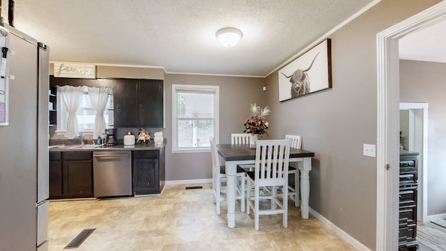 kitchen with a textured ceiling, sink, appliances with stainless steel finishes, dark brown cabinetry, and crown molding