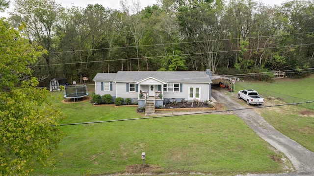 view of front of house with a trampoline, a storage shed, and a front yard