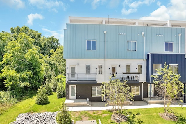 rear view of property with a patio, a balcony, and a yard