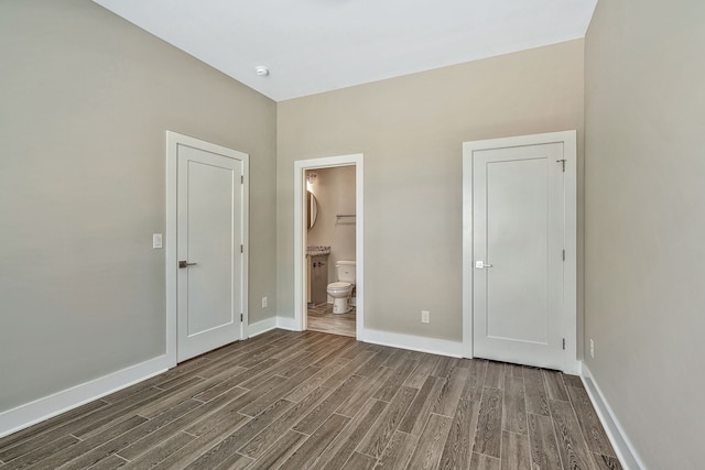 unfurnished bedroom with connected bathroom and dark hardwood / wood-style flooring