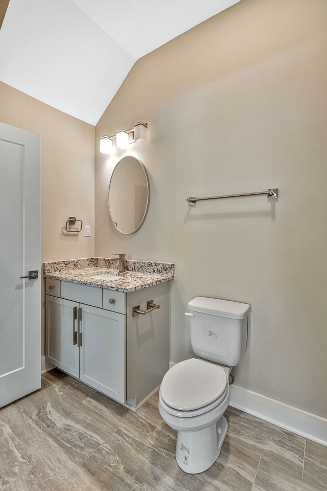 bathroom with lofted ceiling, vanity, and toilet