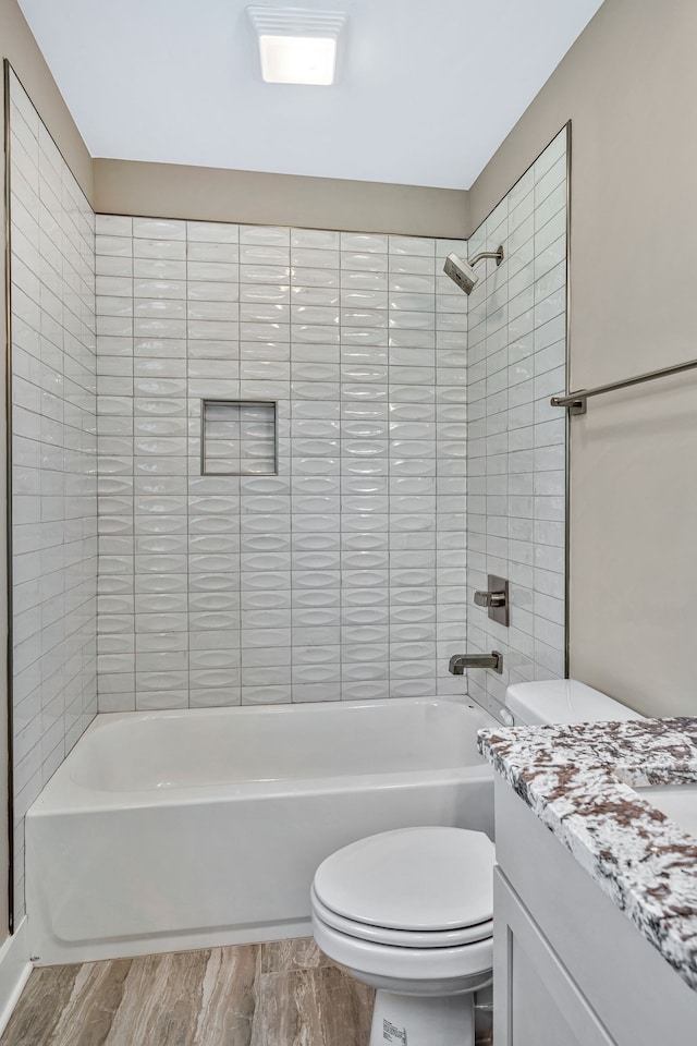 full bathroom with hardwood / wood-style floors, vanity, tiled shower / bath combo, and toilet