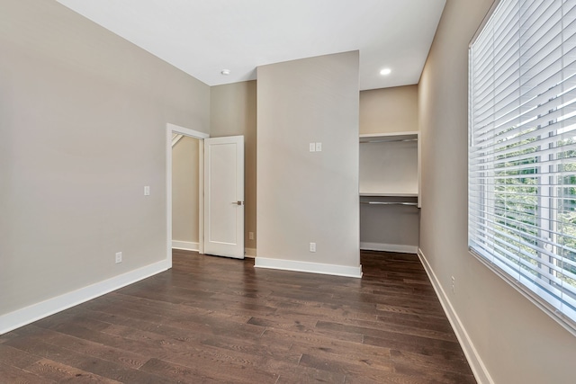 unfurnished bedroom with a spacious closet, dark hardwood / wood-style floors, and a closet