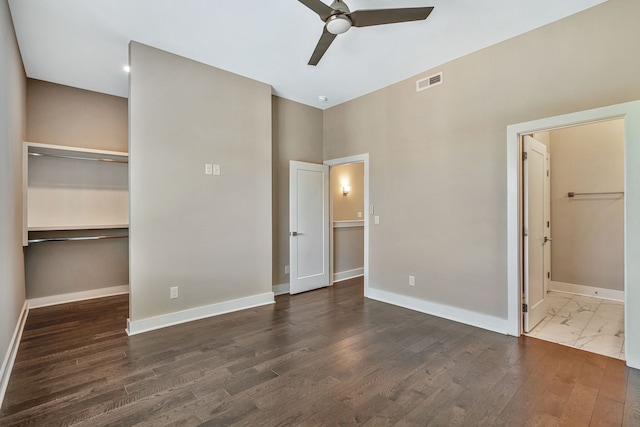 unfurnished bedroom featuring ceiling fan, a closet, dark hardwood / wood-style floors, and a spacious closet