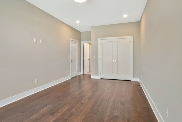 unfurnished bedroom featuring a closet and dark hardwood / wood-style flooring