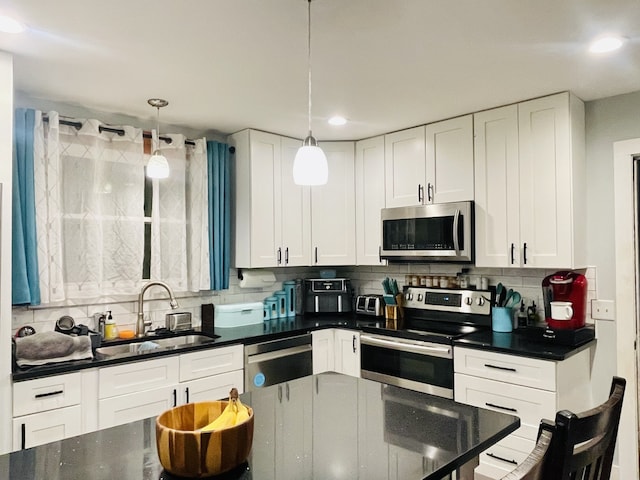 kitchen with white cabinetry, stainless steel appliances, sink, and pendant lighting