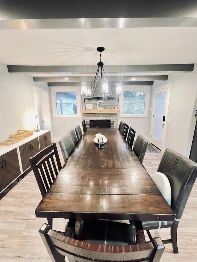 dining space with a chandelier, light hardwood / wood-style flooring, and a large fireplace