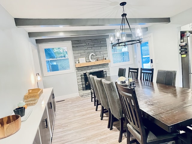 dining space with an inviting chandelier, beamed ceiling, and light wood-type flooring