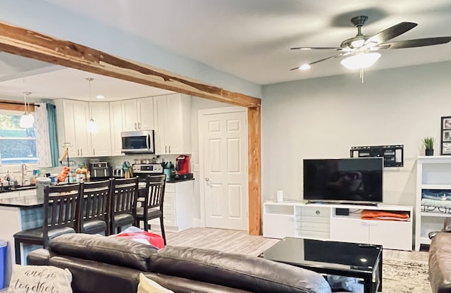 living room with beamed ceiling, hardwood / wood-style floors, sink, and ceiling fan