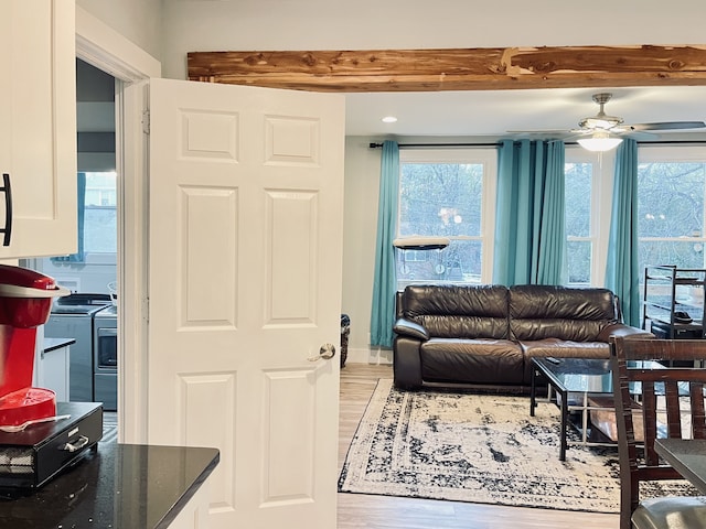 living room featuring light hardwood / wood-style flooring, beam ceiling, and ceiling fan