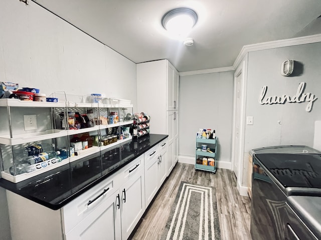 kitchen with white cabinetry, crown molding, hardwood / wood-style floors, and washing machine and clothes dryer