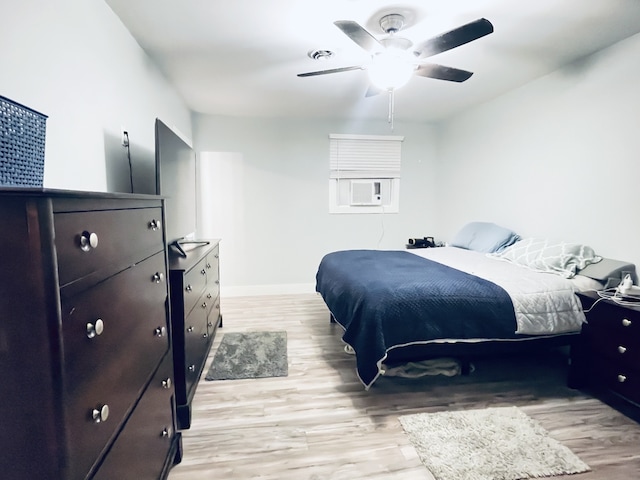 bedroom featuring light hardwood / wood-style floors, cooling unit, and ceiling fan