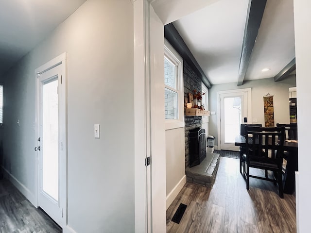 corridor featuring beam ceiling, plenty of natural light, and dark hardwood / wood-style floors