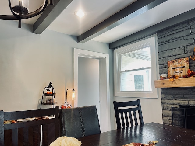 dining space with dark wood-type flooring, beamed ceiling, and a fireplace