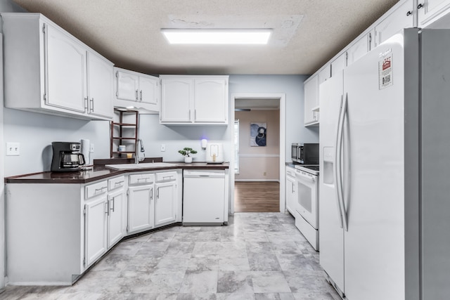 kitchen featuring a textured ceiling, white appliances, white cabinetry, and sink