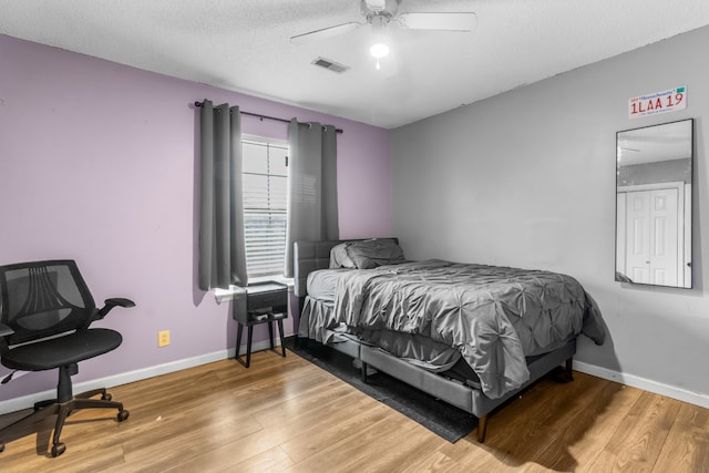 bedroom with ceiling fan, hardwood / wood-style floors, and a textured ceiling