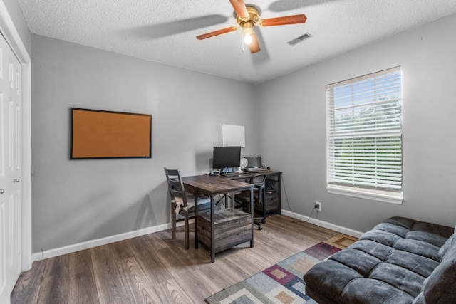 home office featuring ceiling fan, hardwood / wood-style flooring, and a textured ceiling