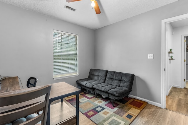 interior space featuring ceiling fan, a textured ceiling, and light hardwood / wood-style flooring