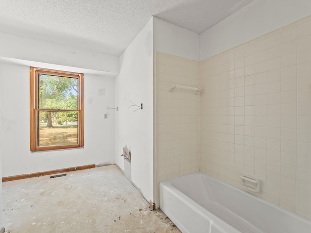 bathroom featuring a textured ceiling and tiled shower / bath combo