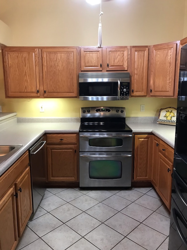 kitchen with stainless steel appliances, light tile patterned flooring, and sink