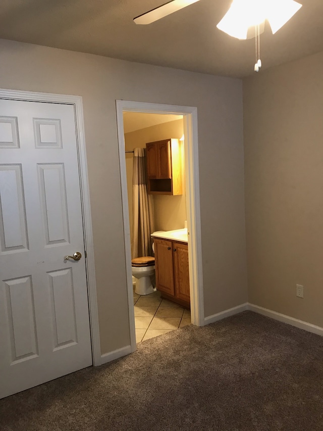 unfurnished bedroom featuring ceiling fan, ensuite bath, and light carpet