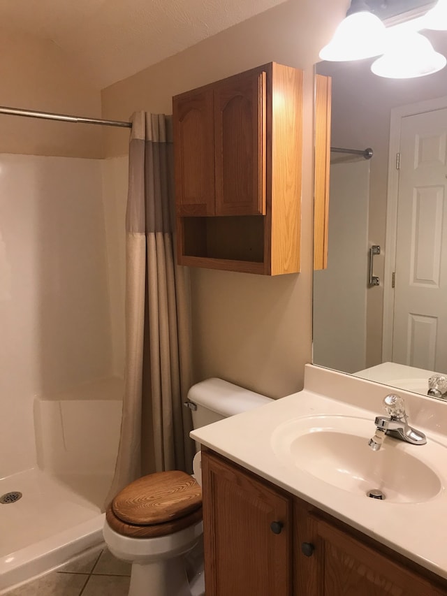 bathroom featuring walk in shower, vanity, toilet, and tile patterned floors