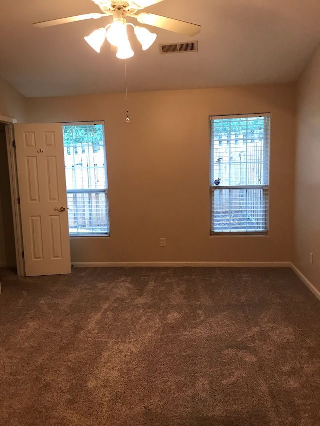 carpeted spare room featuring ceiling fan and a wealth of natural light