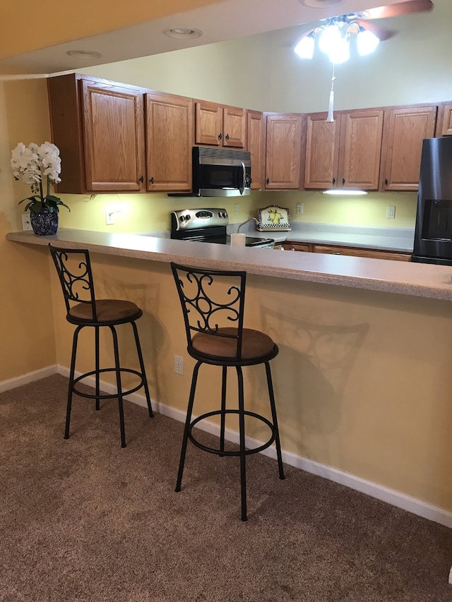 kitchen featuring lofted ceiling, dark carpet, stainless steel appliances, and a breakfast bar