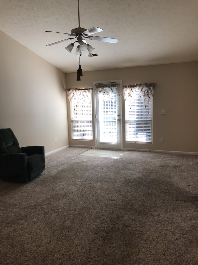 unfurnished living room featuring ceiling fan and carpet