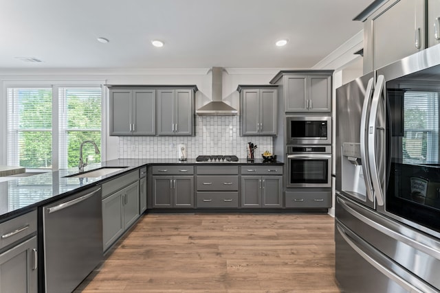 kitchen featuring sink, wall chimney range hood, gray cabinetry, appliances with stainless steel finishes, and hardwood / wood-style floors