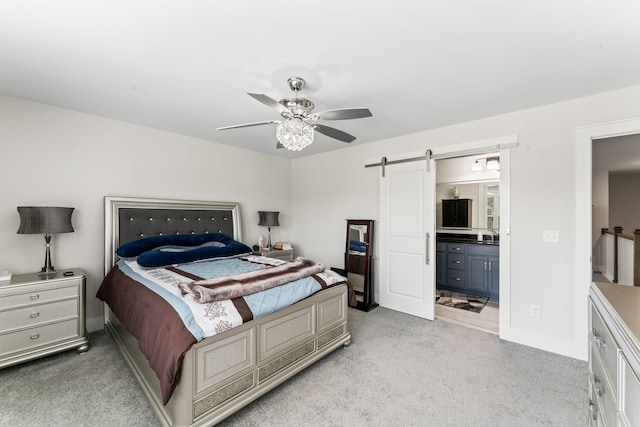 carpeted bedroom with ceiling fan, ensuite bathroom, and a barn door