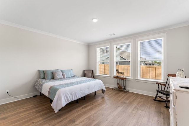 bedroom with multiple windows, hardwood / wood-style floors, and crown molding