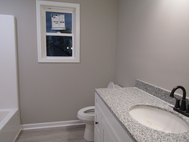 bathroom featuring vanity, a bathtub, hardwood / wood-style floors, and toilet