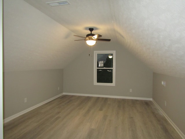 bonus room featuring wood-type flooring, vaulted ceiling, a textured ceiling, and ceiling fan