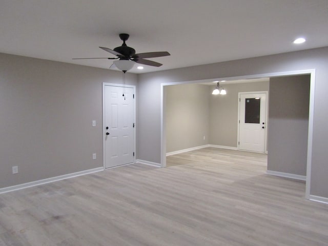 spare room with ceiling fan with notable chandelier and light hardwood / wood-style flooring