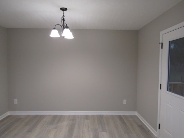 spare room featuring a notable chandelier and light hardwood / wood-style flooring