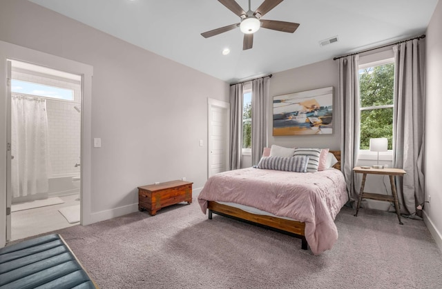 bedroom featuring ceiling fan, light colored carpet, and ensuite bathroom