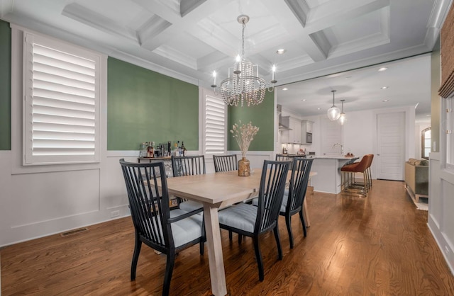 dining space featuring beam ceiling, hardwood / wood-style floors, and crown molding