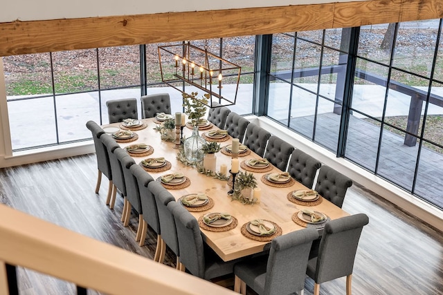 dining space with a wealth of natural light, a notable chandelier, and hardwood / wood-style flooring