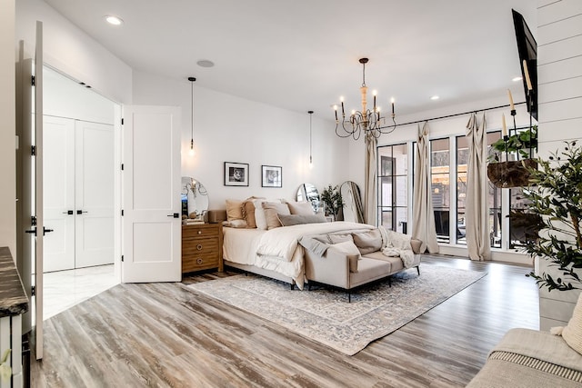 bedroom featuring access to exterior, an inviting chandelier, and hardwood / wood-style floors