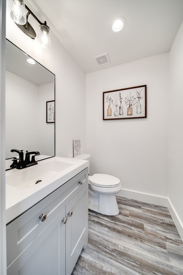 bathroom with vanity, toilet, and hardwood / wood-style floors