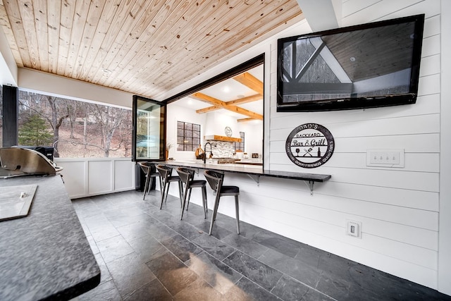 interior space featuring wooden walls, wooden ceiling, and vaulted ceiling with beams