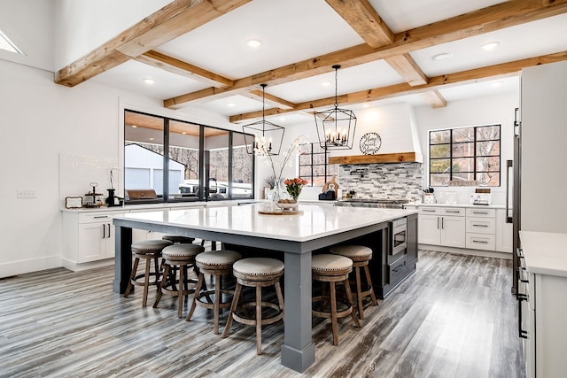 kitchen featuring beamed ceiling, hardwood / wood-style floors, white cabinets, and tasteful backsplash