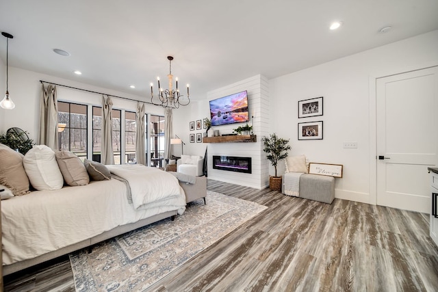 bedroom with a notable chandelier, a fireplace, hardwood / wood-style flooring, and access to outside