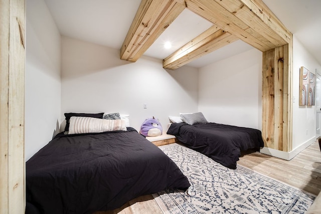 bedroom with beam ceiling and hardwood / wood-style flooring