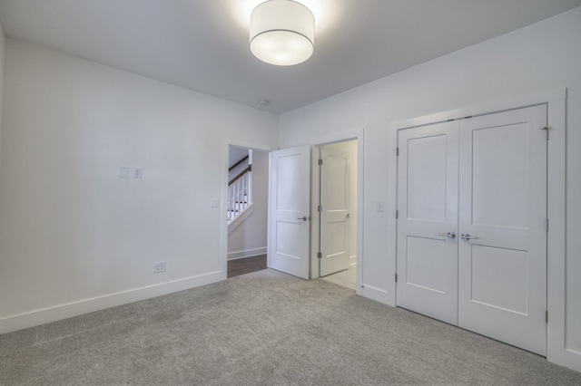 unfurnished bedroom featuring light colored carpet and a closet